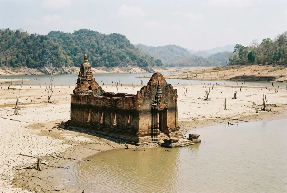 Brick temple ruin standing in shallow reservoir water at low level